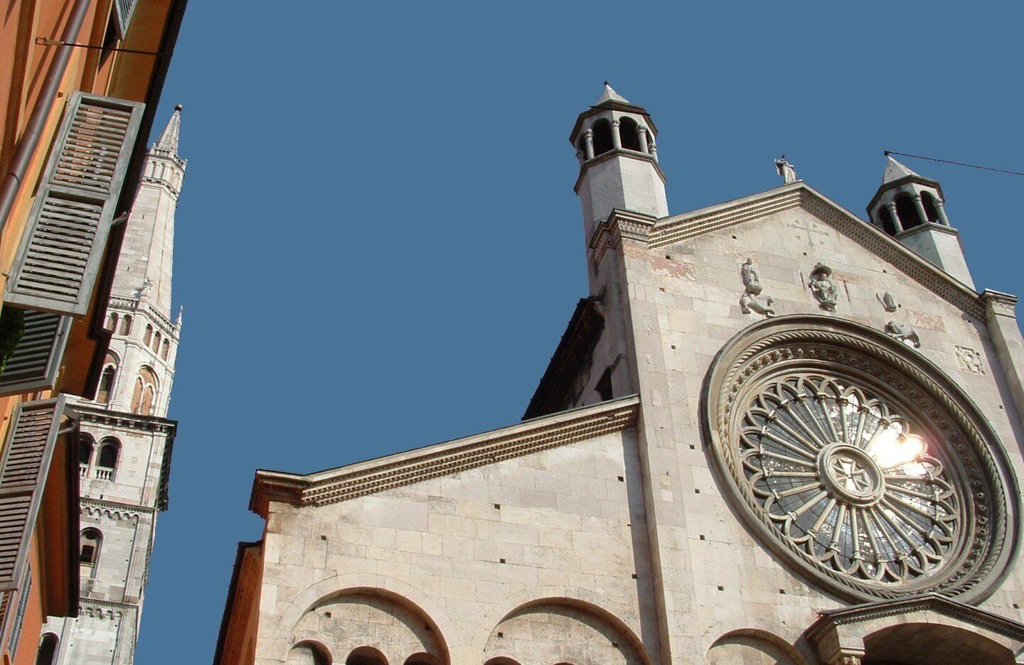 Die romanische Fassade und die Fensterrose des Doms von Modena, links der aufragende Glockenturm Ghirlandina