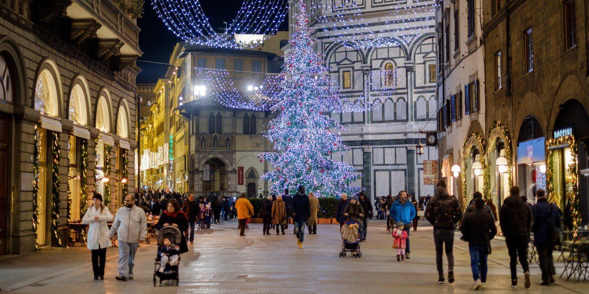 Familien auf einer geschmückten Straße in Florenz, auf dem Weg zum beleuchteten Weihnachtsbaum auf der Piazza del Duomo