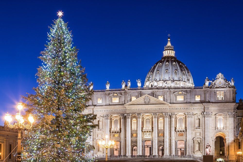Der beleuchtete Weihnachtsbaum auf dem Petersplatz in Rom, vor der Fassade und der Kuppel des Petersdoms