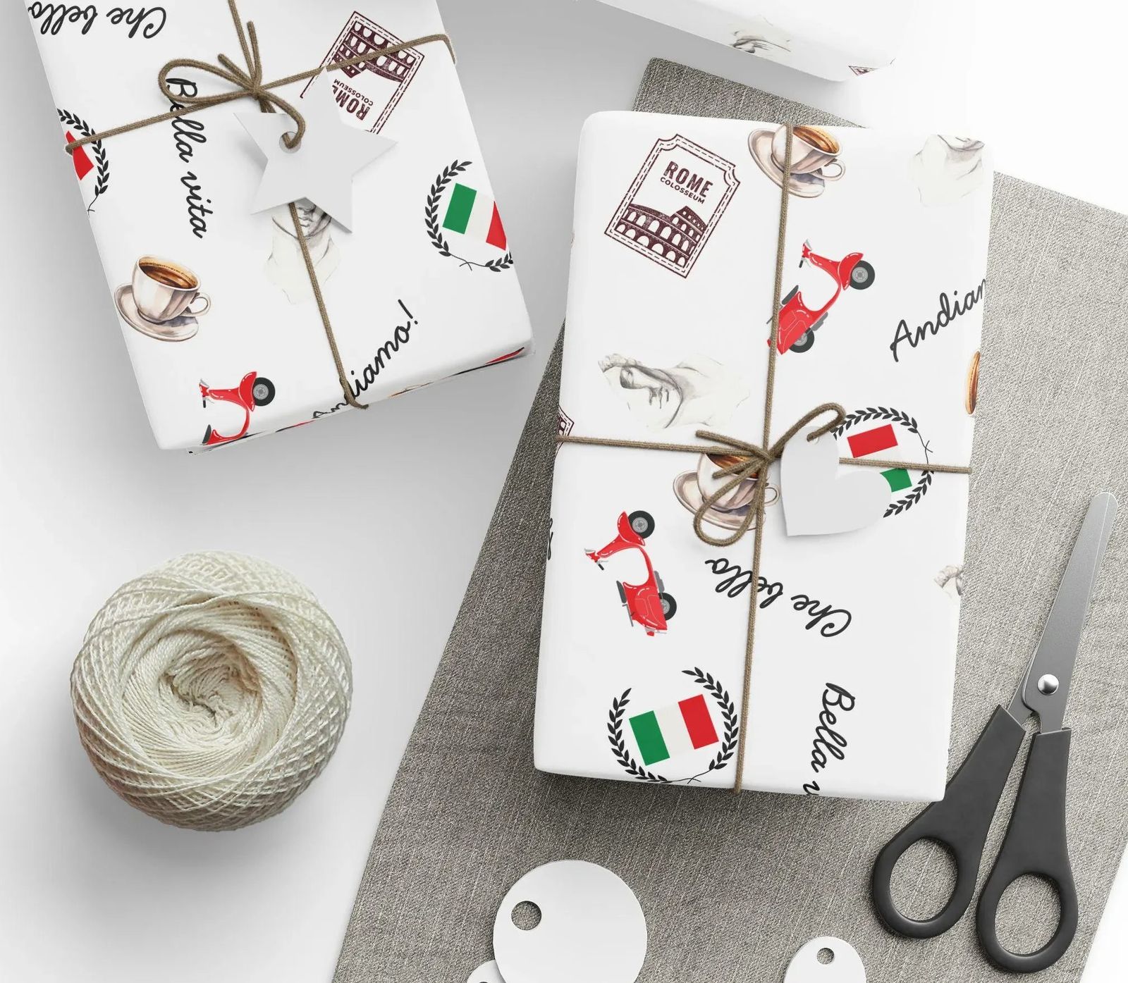 Presents wrapped in Italy-themed paper – scooters, flags, espresso cups – tied with twine, beside scissors and a ball of thread