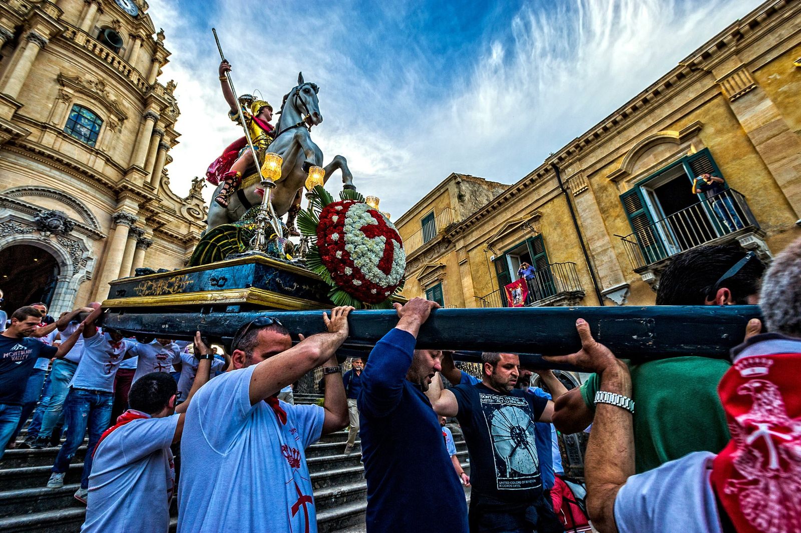Los portadores llevan a hombros la estatua ecuestre de san Jorge ante una iglesia barroca, durante la fiesta de una localidad siciliana