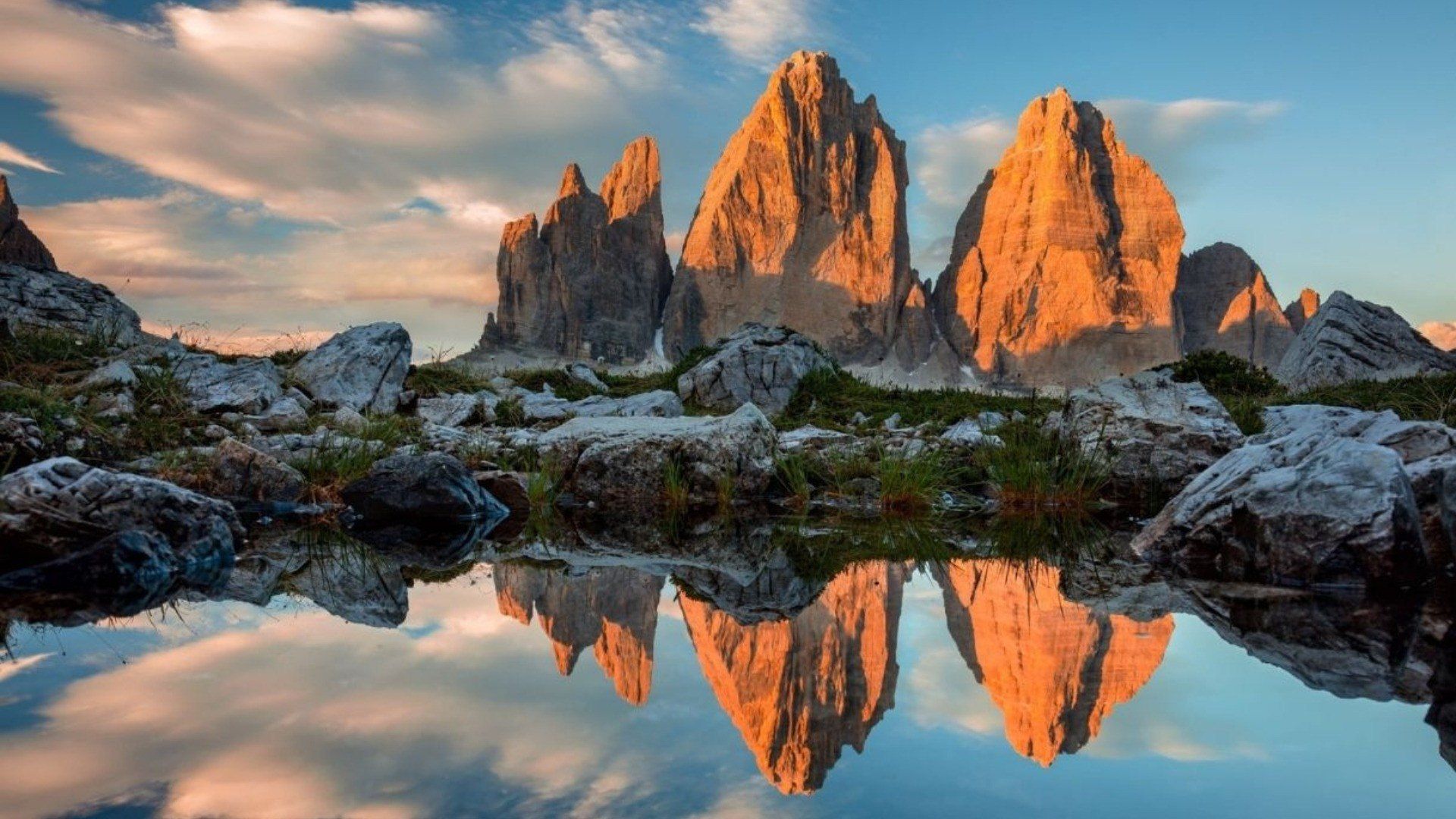 Las Tres Cimas de Lavaredo con una luz rasante y dorada, reflejadas en una laguna de montaña